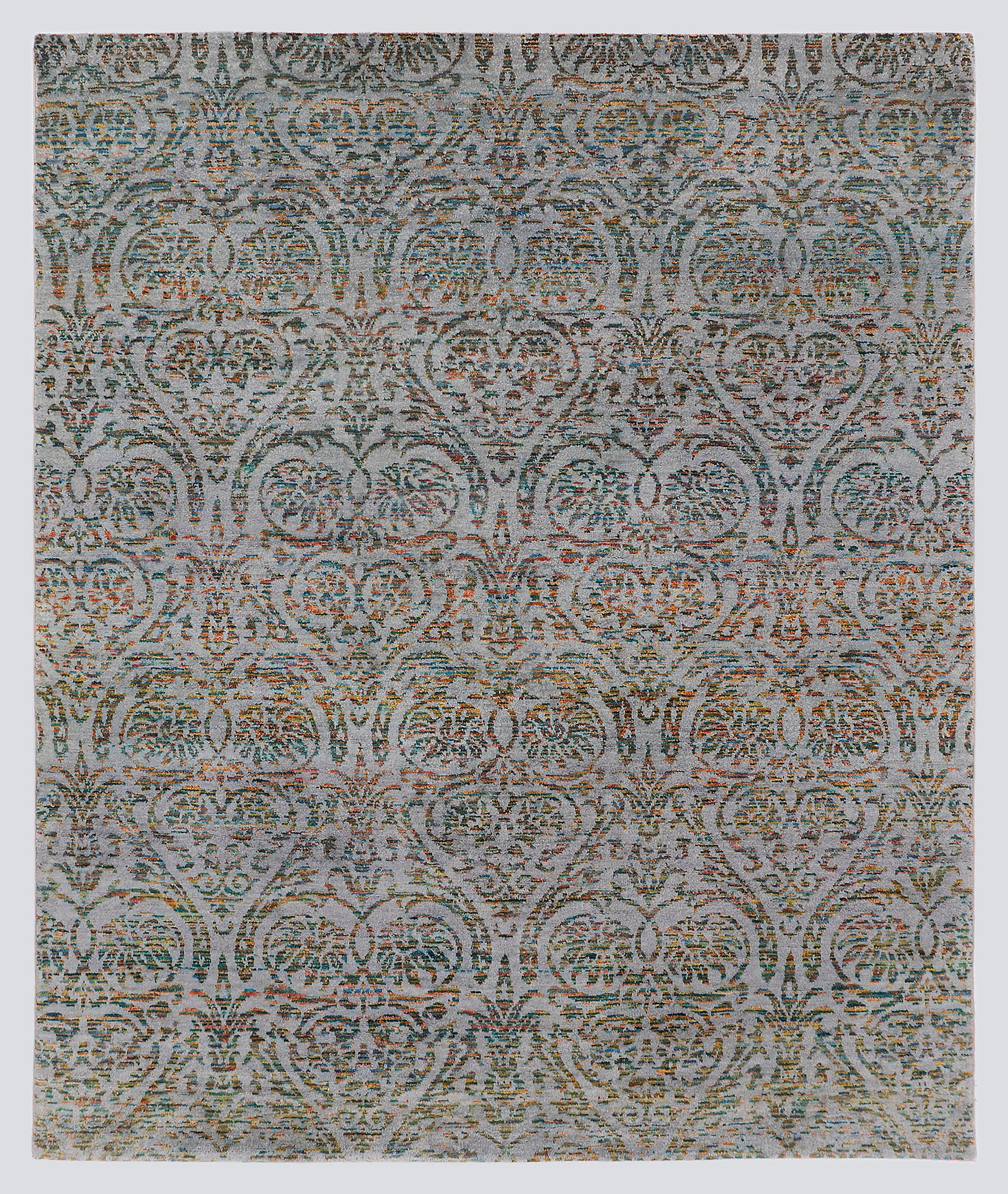 A full view of a modern transitional hand-knotted rug from the Nomad Series, featuring a repeating classical palmette pattern rendered in multi-colored, tie-dyed wool over a silvery-grey foundation.